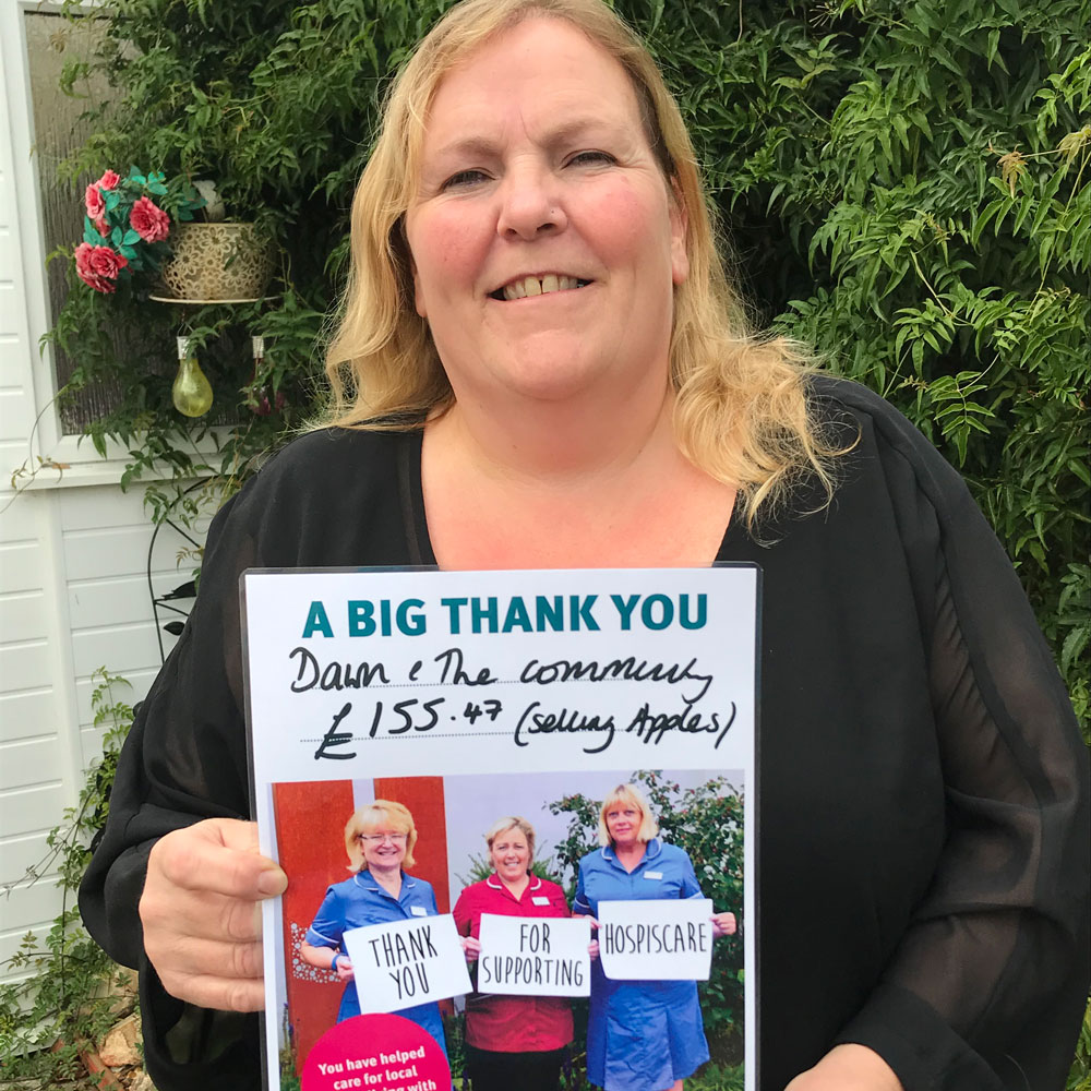 A woman holding up a Hospiscare thank you poster