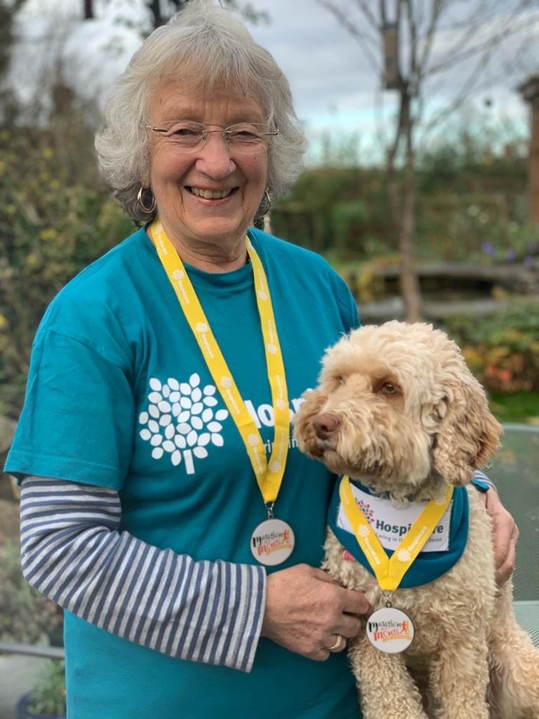 An elderly woman and her dog wearing medals