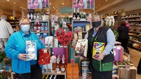 Two women wearing masks holding Easter Eggs in a Waitrose shop