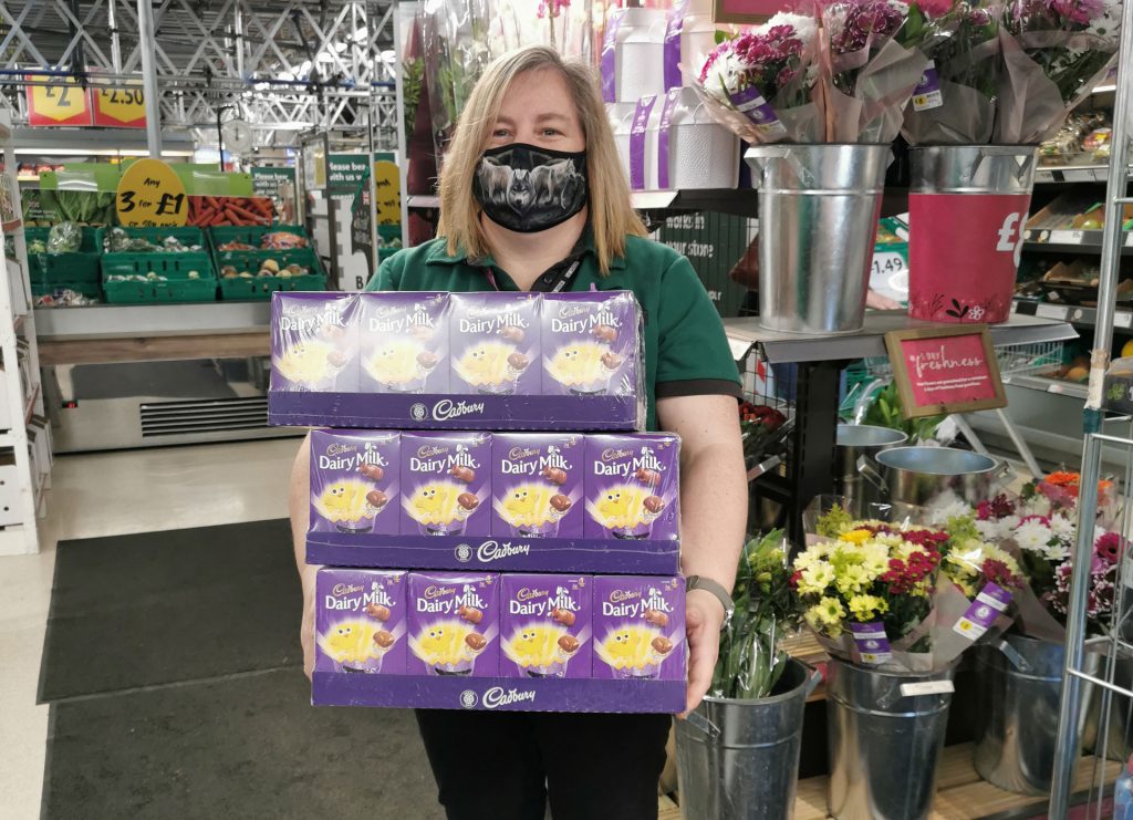 A woman holding a stack of Easter Eggs in Morrisons