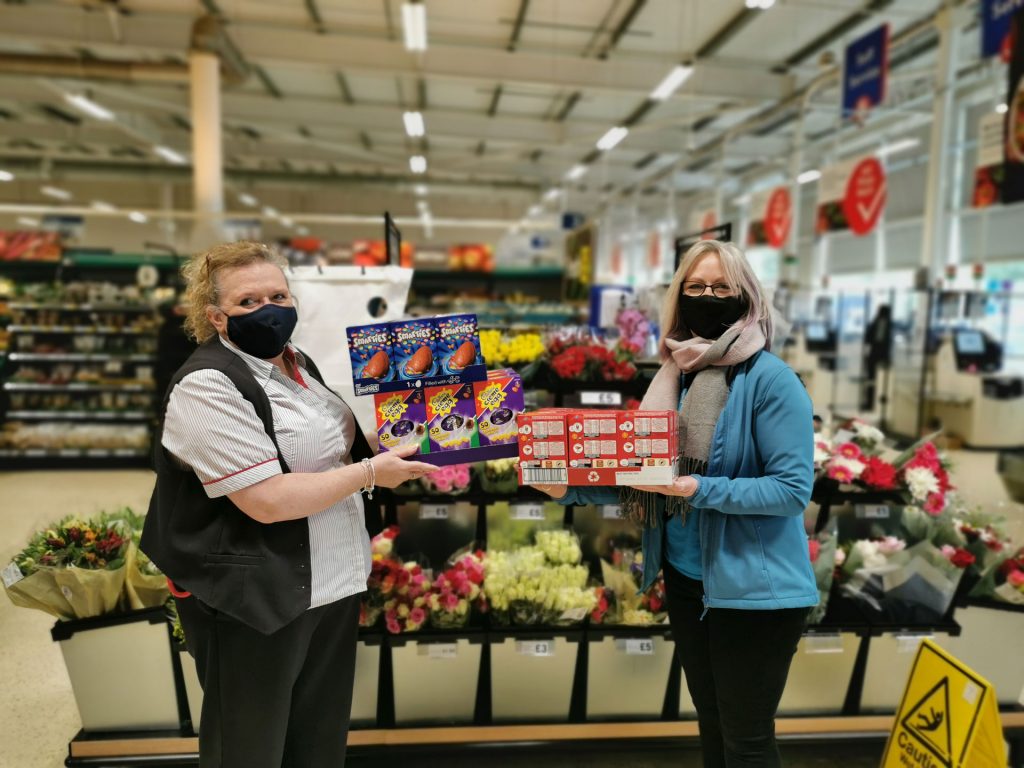Two women wearing masks holding Easter Eggs in a supermarket