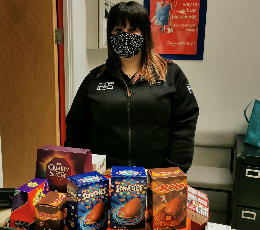 A Tesco worker standing with Easter Eggs in front of her