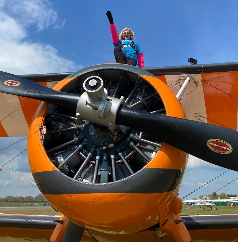 A woman strapped to the wings of a yellow bi-plane