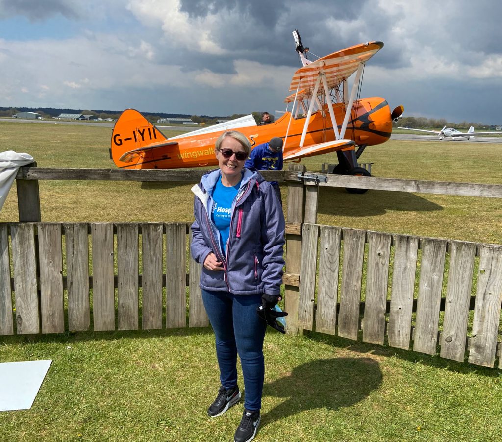 A woman standing in front of a yellow bi-plane