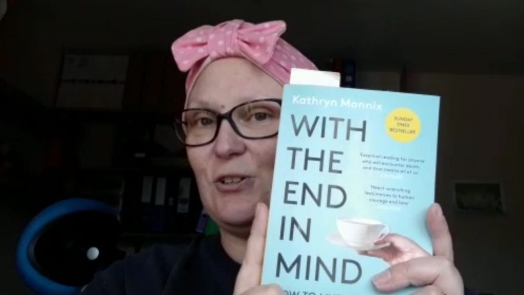 A woman wearing a pink headscarf holding a book