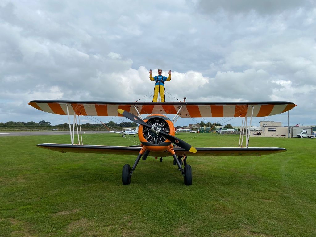 A man strapped to the wings of a vintage bi-plane