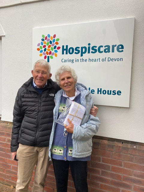 An elderly man and woman in front of a Hospiscare sign