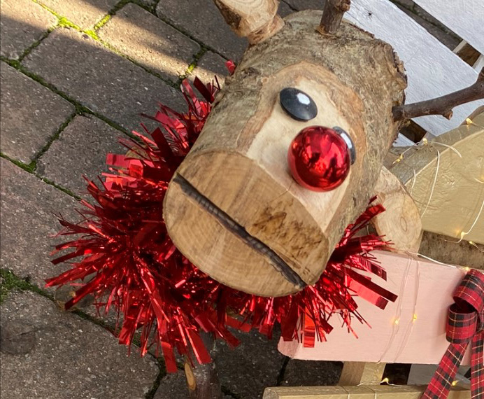 A log reindeer with tinsel and a bauble nose