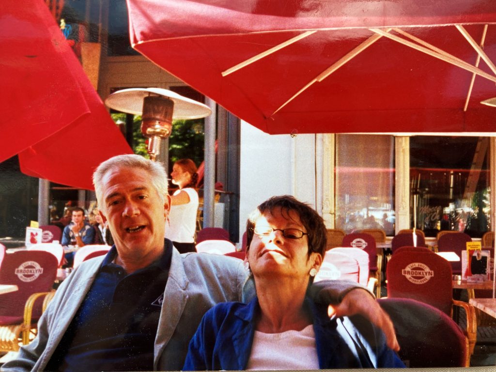 A man and woman smiling in an outdoor seating area