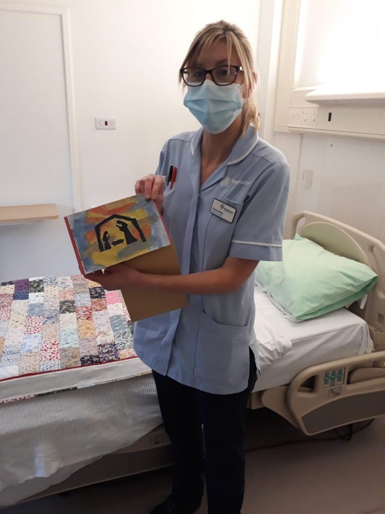 A nurse in a mask holding a Christmas card
