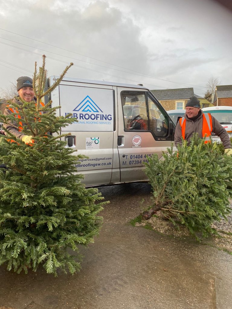 Two men with Christmas trees by a van