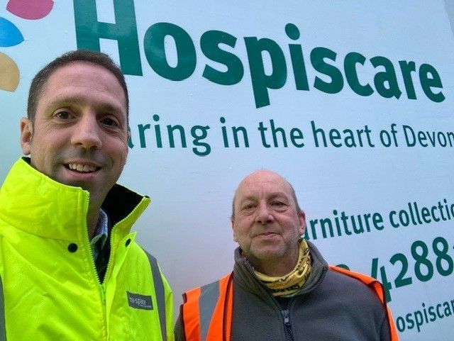 Two men in front of a Hospiscare sign