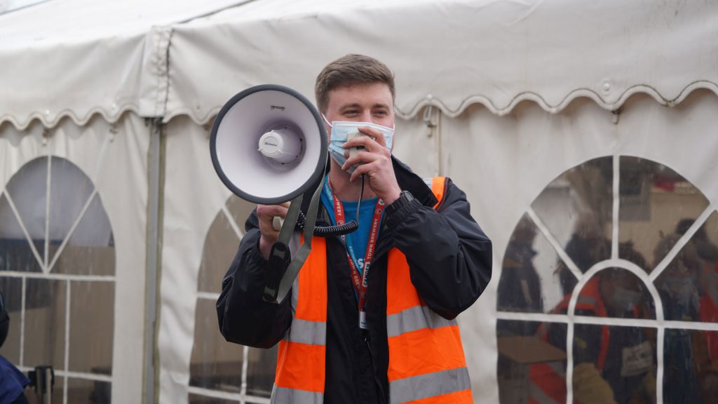 A man wearing a high vis and speaking through a megaphone