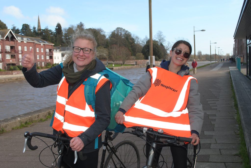Two volunteers wearing high vis orange vests on bicycles