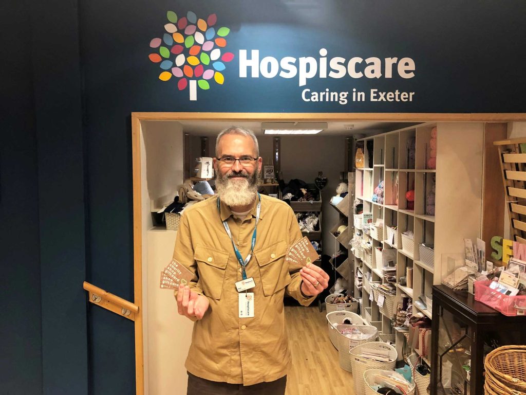 A man holding gift cards in a Hospiscare charity shop