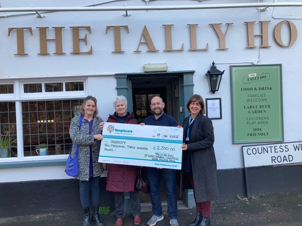 Four people holding a big cheque outside the Tally Ho pub