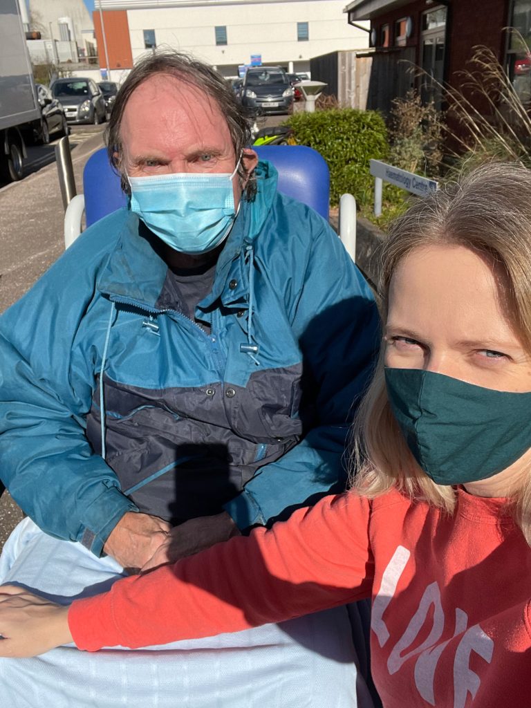 A man and woman wearing masks outside a hospital