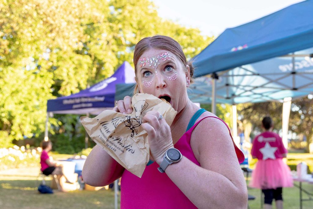 A woman in pink eating a pasty