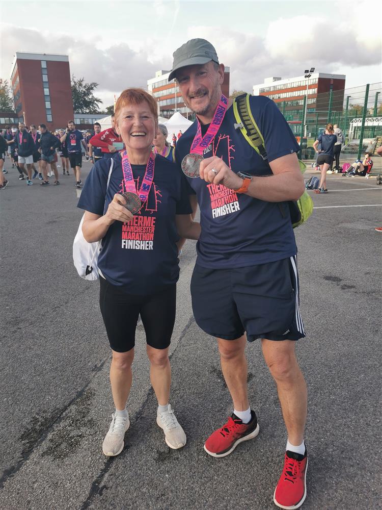 A man and a woman wearing running gear holding medals