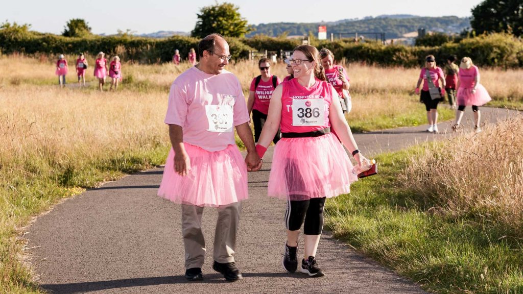 A man and woman holding hands wearing pink tops and tutus