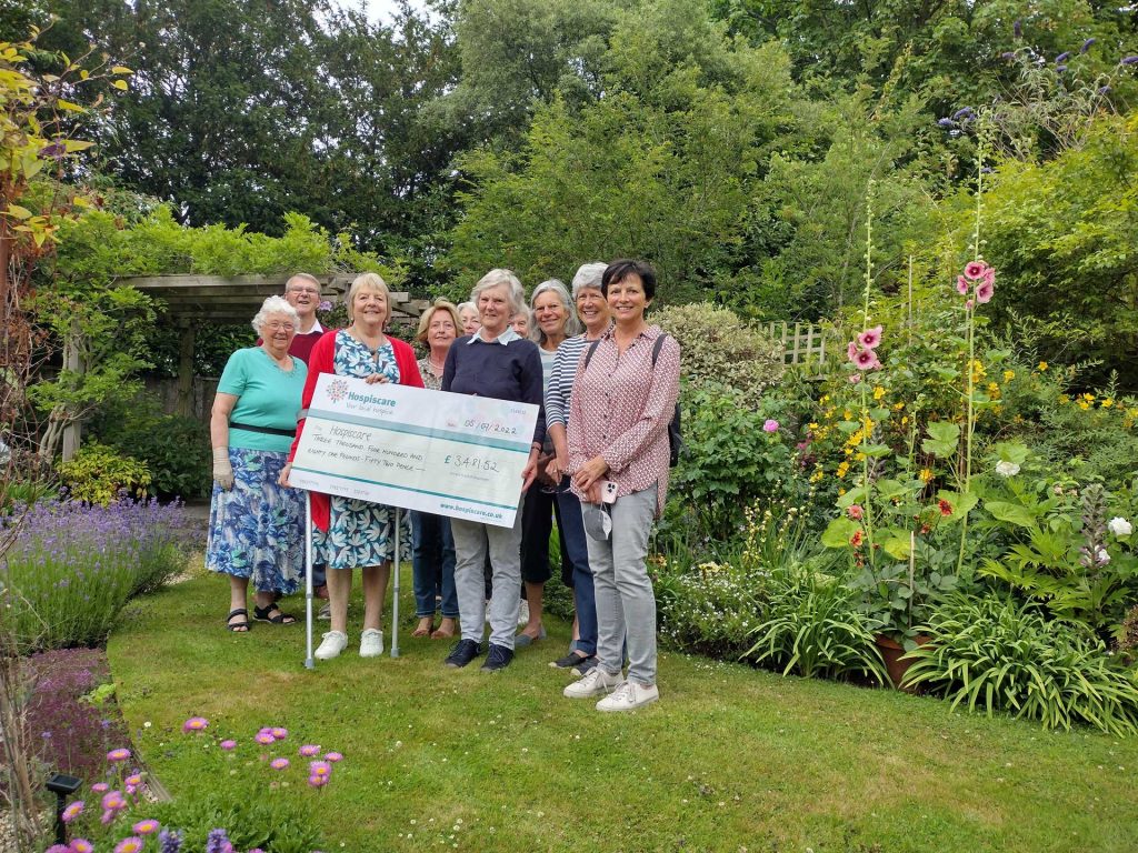 A group of people holding a big cheque in a garden
