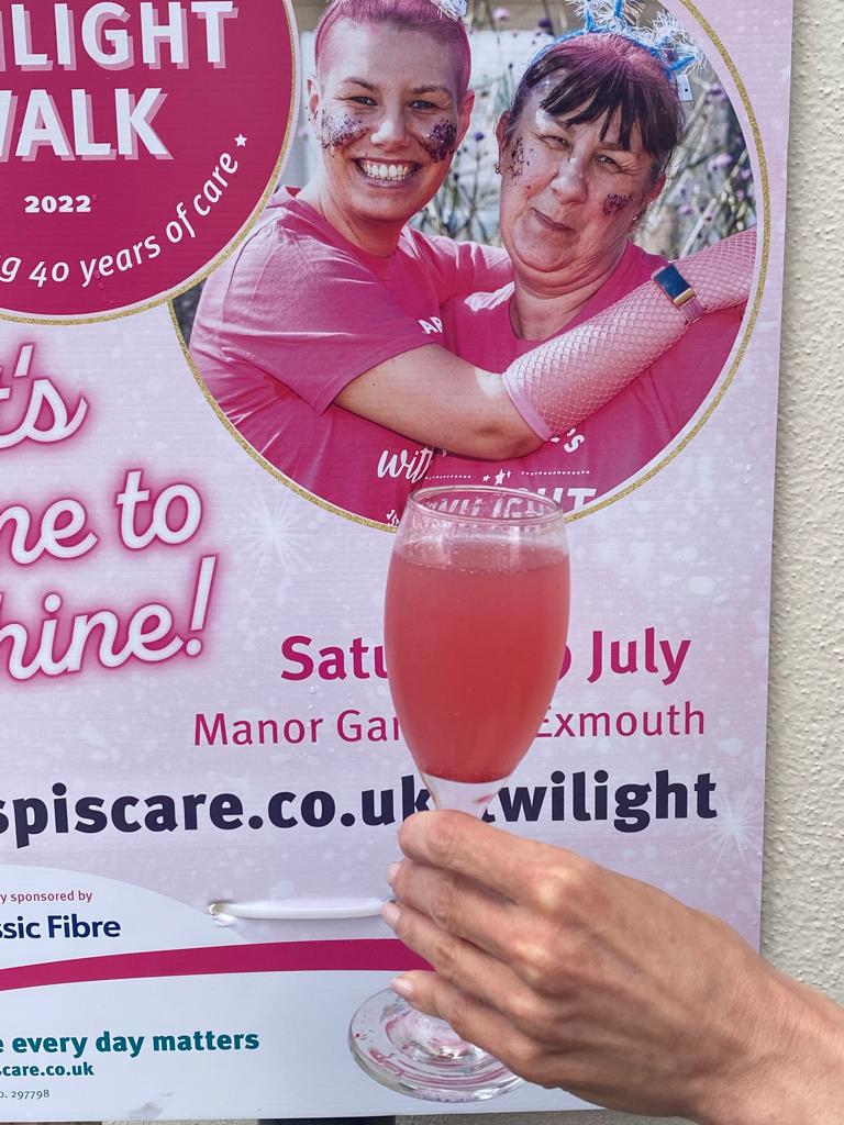A glass of pink fizz in front of a Twilight Walk poster