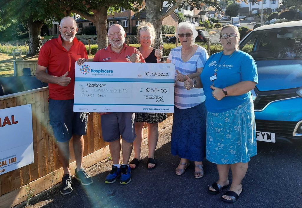 A group of people outside holding a big cheque