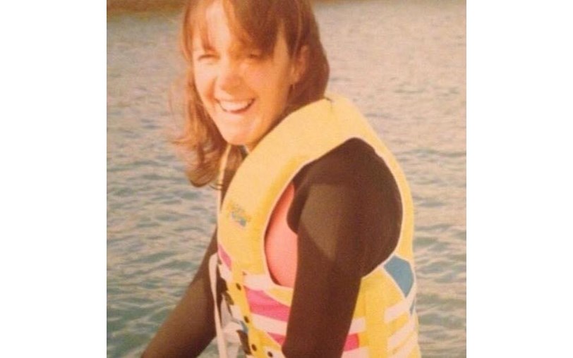 A woman laughing at the camera wearing a life vest