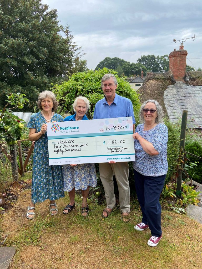 A group of people holding a big cheque in a garden