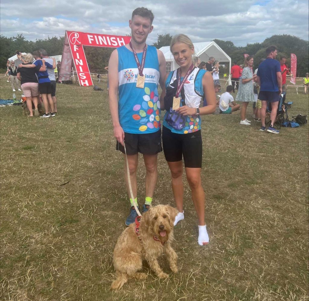 A man and a woman in running vests with a dog