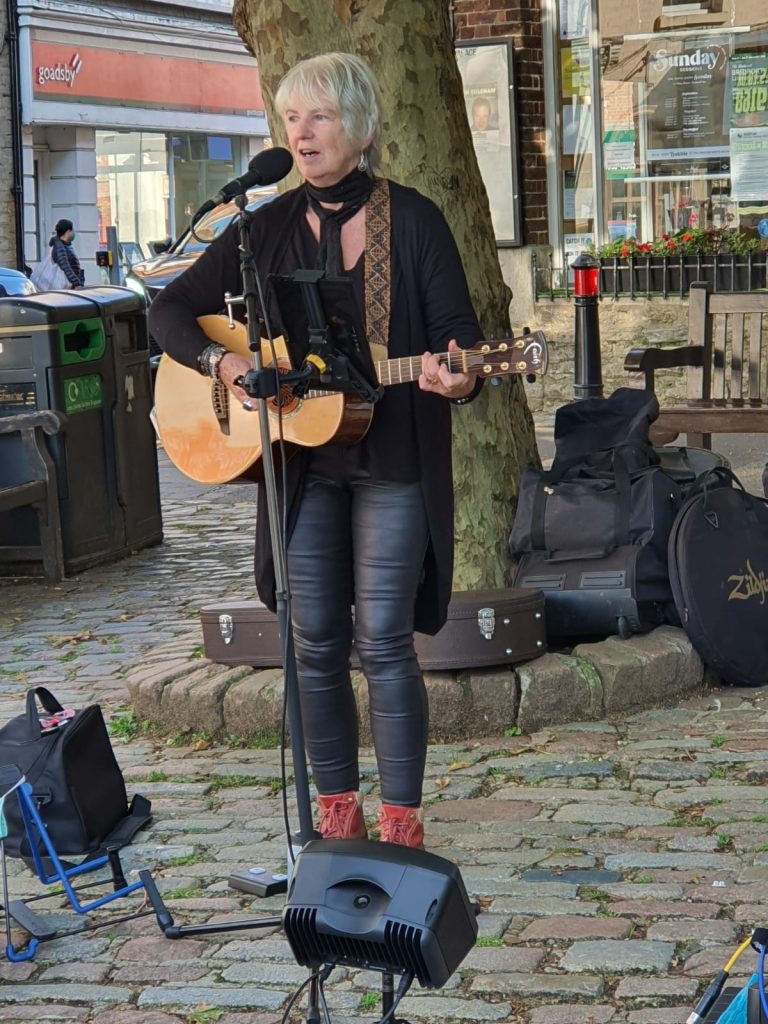 A woman singing and playing guitar outside