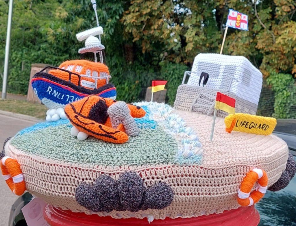 A crocheted sea scene on top of a postbox