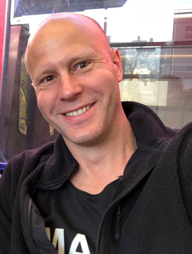 A man wearing black smiling at the camera