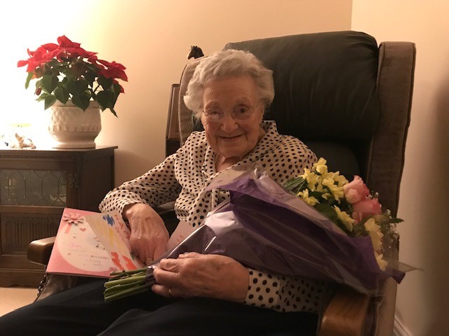 An elderly woman holding a bouquet of flowers