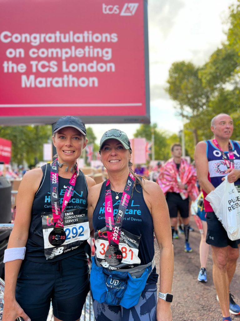 Two women wearing running vests and medals