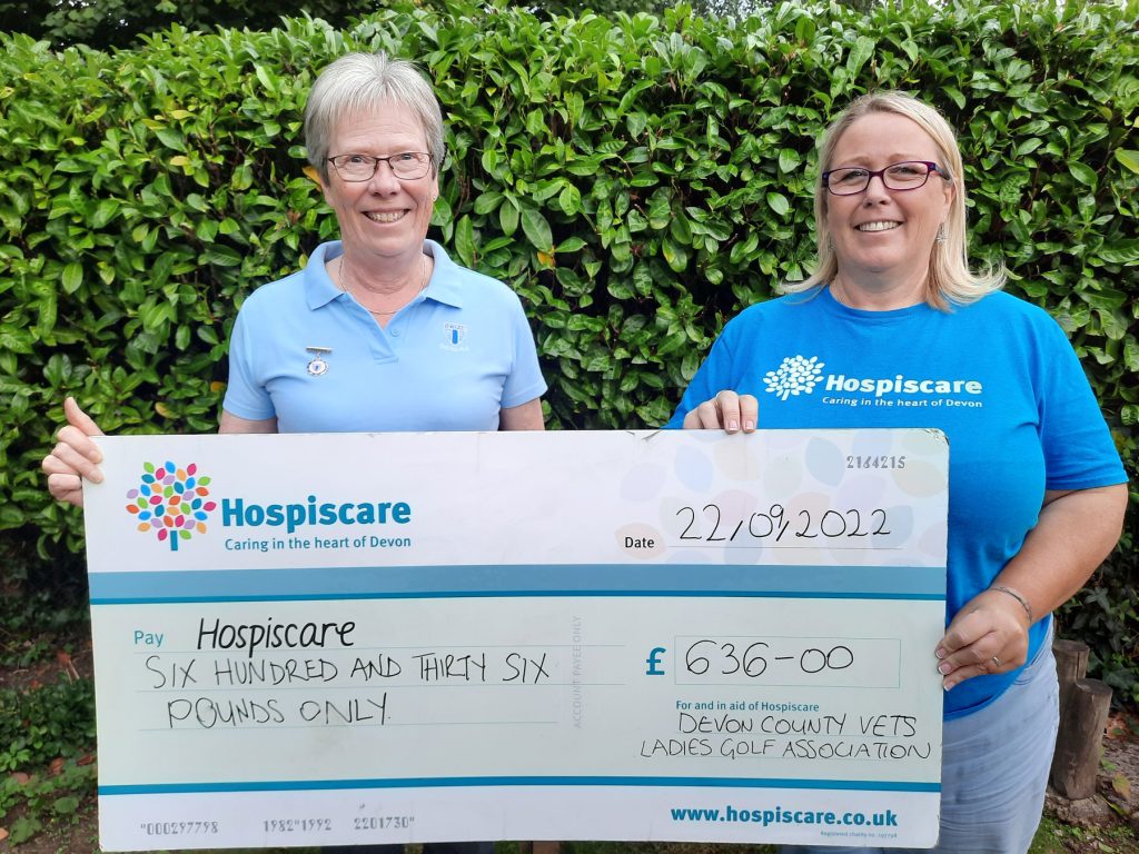 Two women holding a big cheque outside