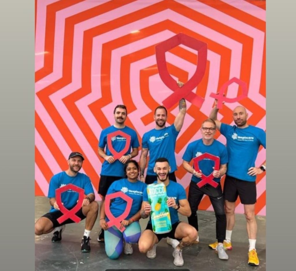 A group of people in Hospiscare t-shirts in front of a geometric background