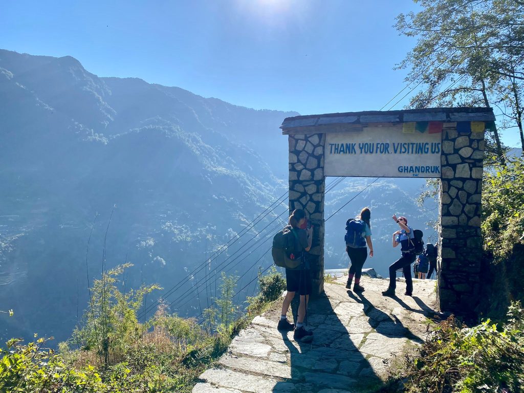 A group of walkers walking under an archway in the Nepal mountains