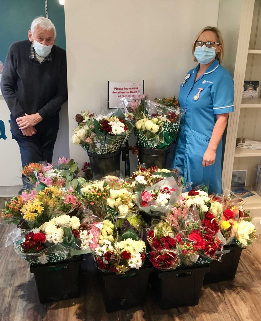 A man and a nurse by buckets of flowers