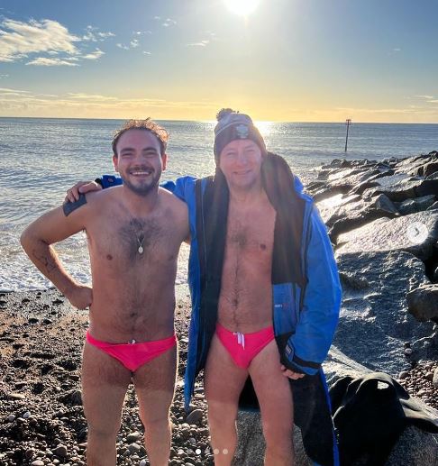 Two men in pink speedos on a beach in winter
