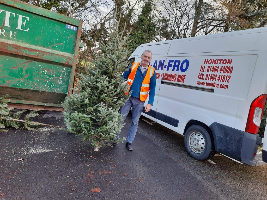 A man with a Christmas tree in front of a to-and-fro van