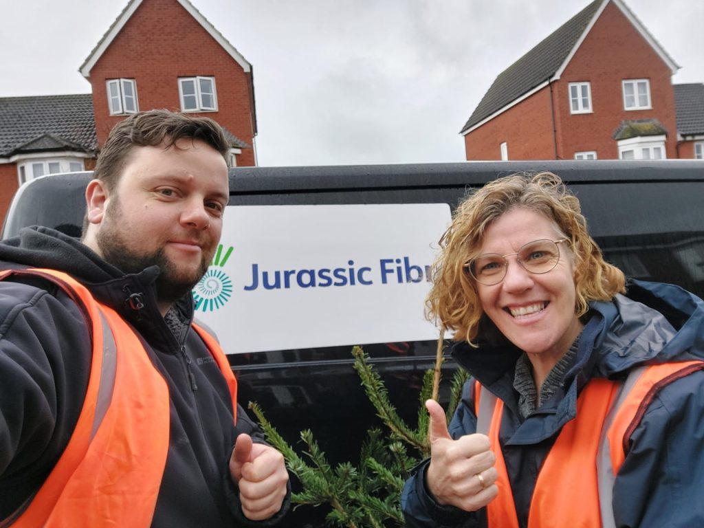 Two people giving thumbs up in front of a Jurassic Fibre van